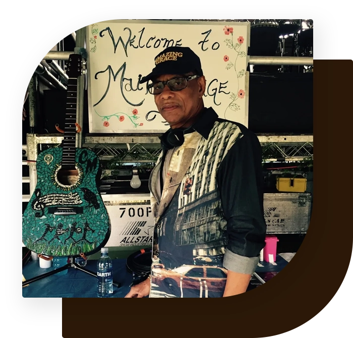 A man standing next to a guitar in front of a sign.