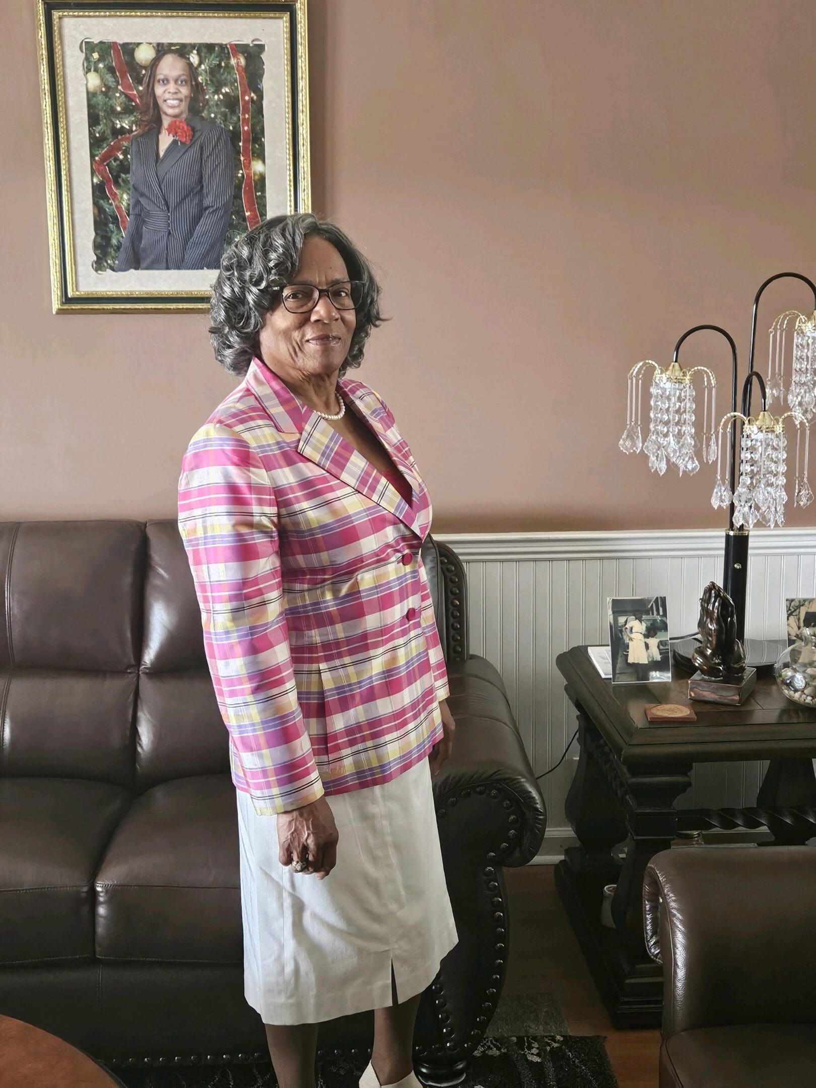 A woman standing in front of a brown leather couch.