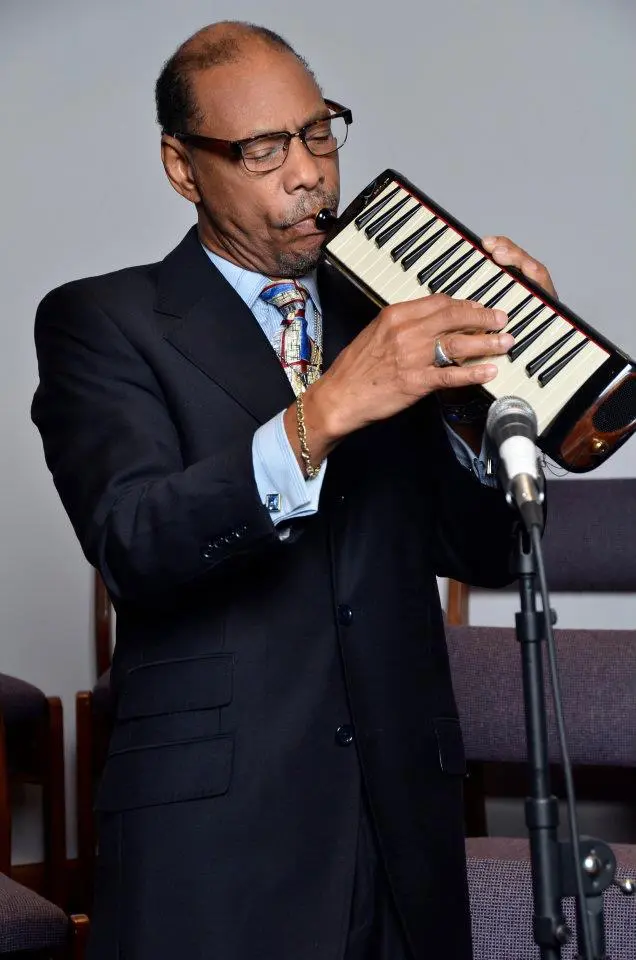 A man in suit playing an instrument on stage.