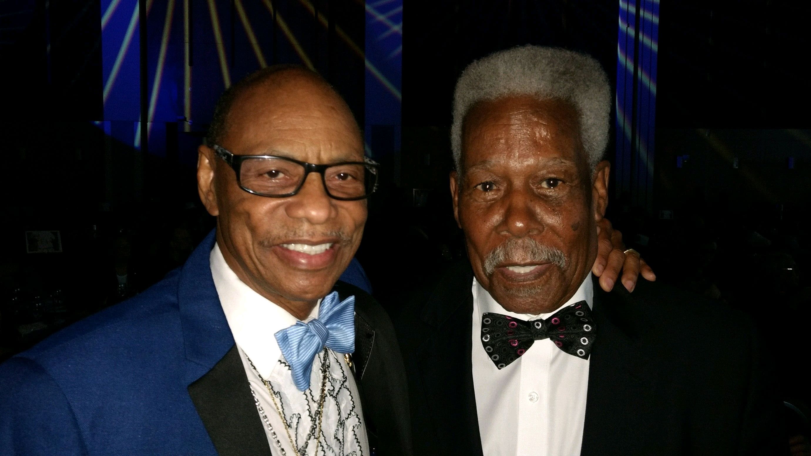 Two men in suits and bow ties posing for a picture.