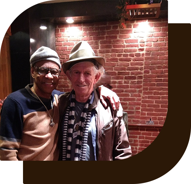 Two men standing next to each other in front of a brick wall.